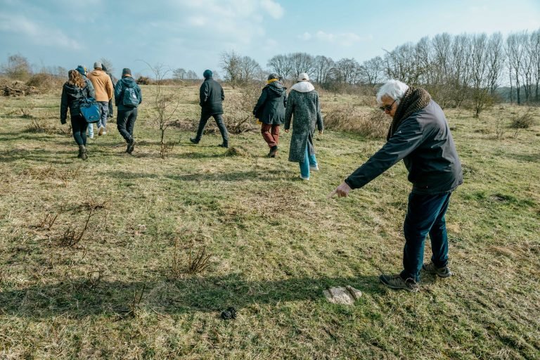 A man pointing towards some dung on the ground of a pasture.