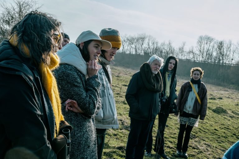 A group of people standing on a pasture in the sun.