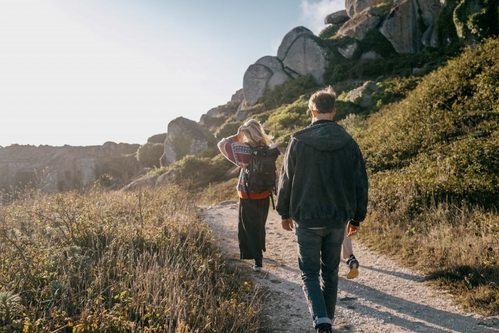 a woman and a man walking on a nature path.