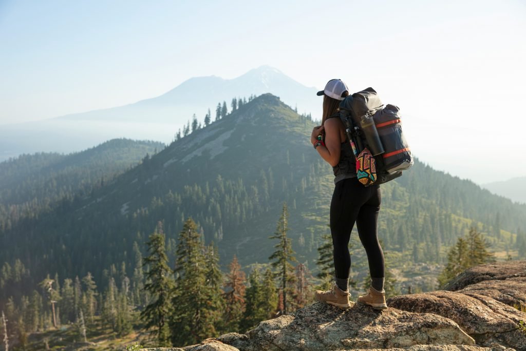 woman standing on top of a hill looking into the distant mountains