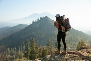 woman standing on top of a hill looking into the distant mountains