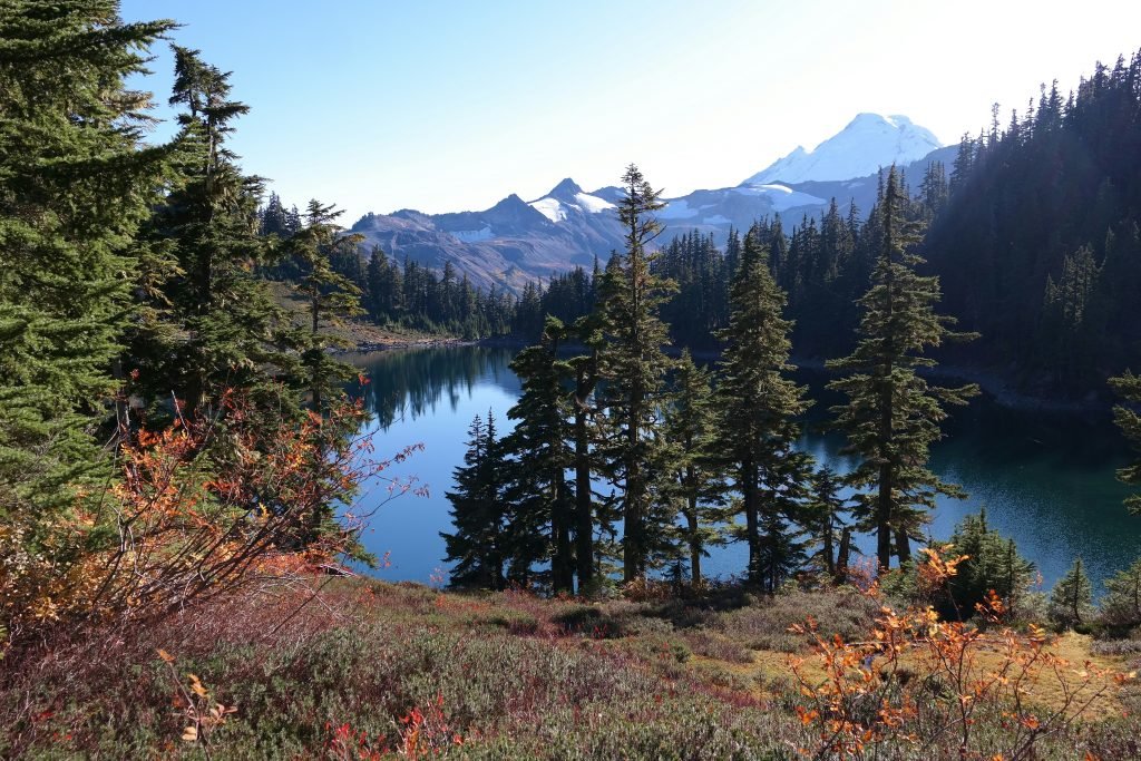 view on a lake in the mountains. the lake is sourrounded by trees an din the background you see another mountain.