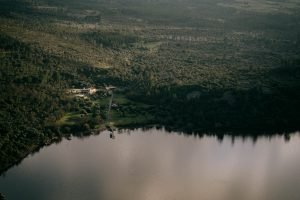 Alternative text: dark green forested landscape with a dark lake and a lakeside property