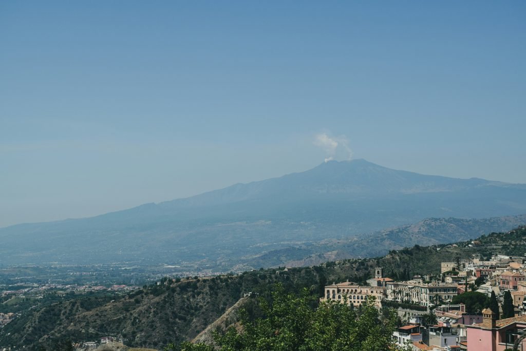 view onto a mountain in scicially with a mall village or city in the foreground