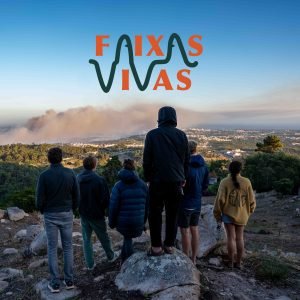 people standing on top of a hill looking into the vally where a wild fire creates a lot of smoke. on the sky a logo saying faixas vivas