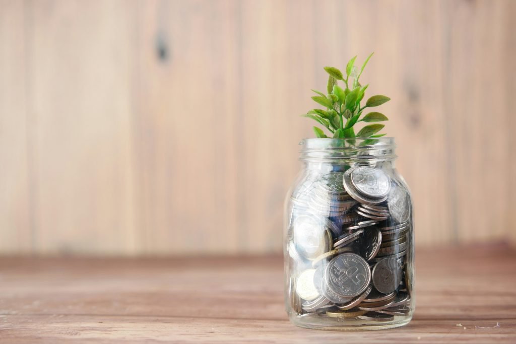 glass jar with coins with small plant growing off the top