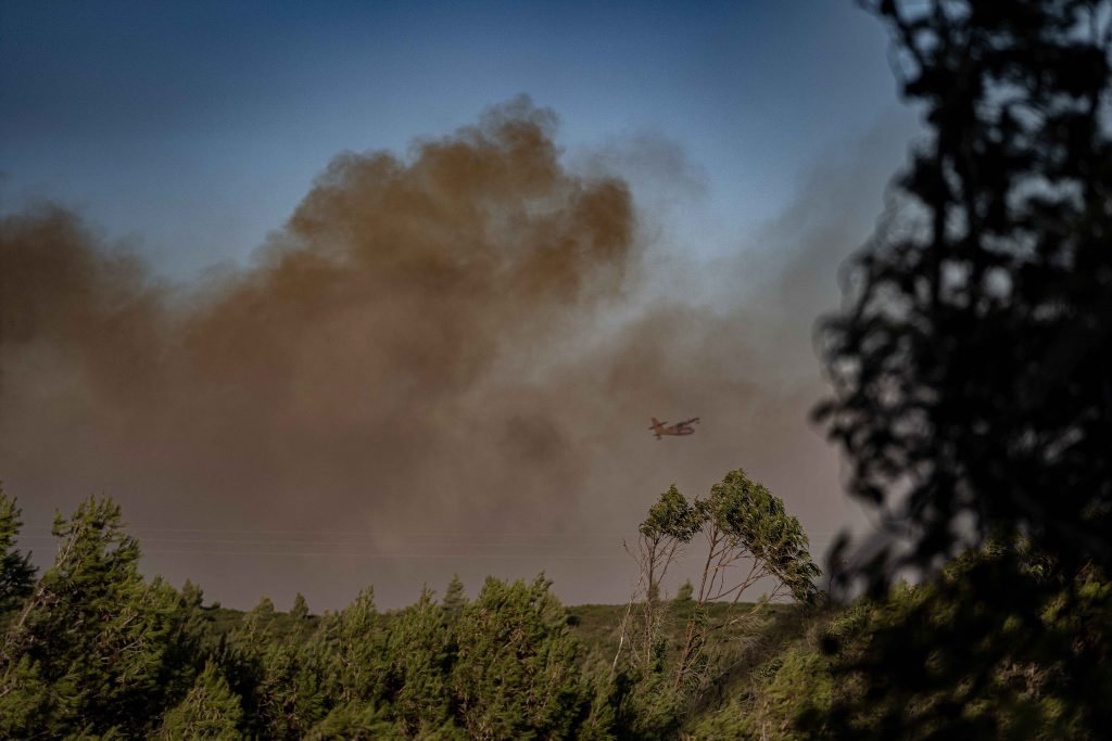 fire fighting airplain passing through wildfire smoke